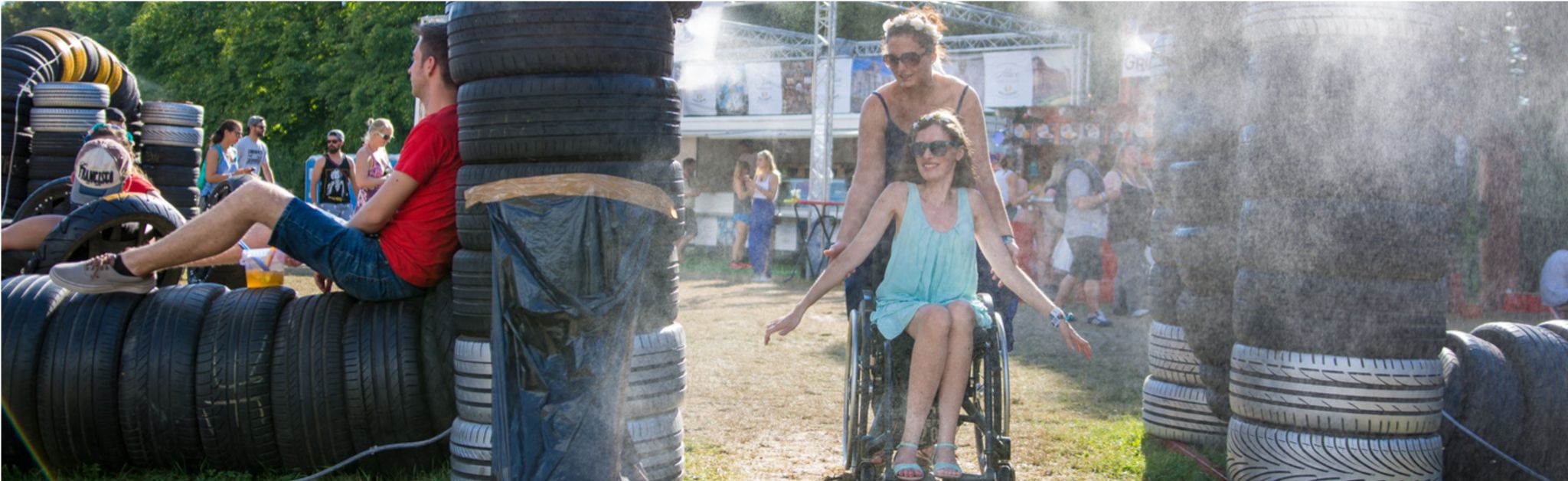 Zwei Frauen auf einem Festival, eine von ihnen sitzt in einem Rollstuhl
