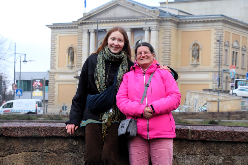 Zwei junge Frauen stehen dicht beeinander vor dem Opernhaus Halle 